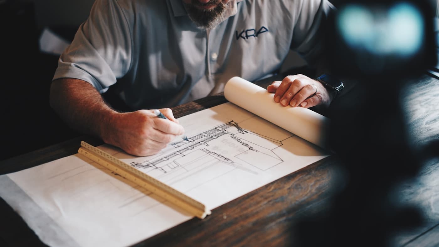 An architect drafting building plans with a scale ruler